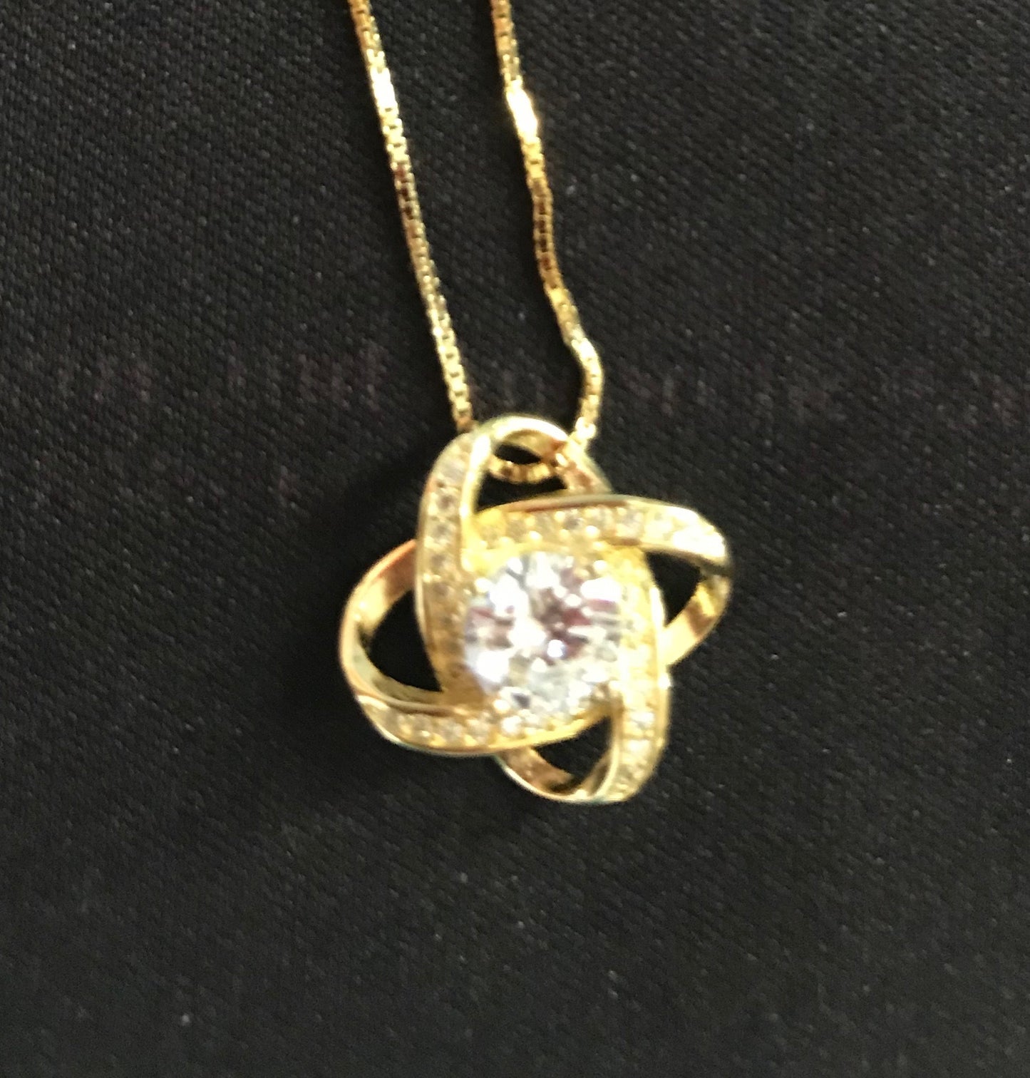 Gold necklace with a diamond pendant on a black background