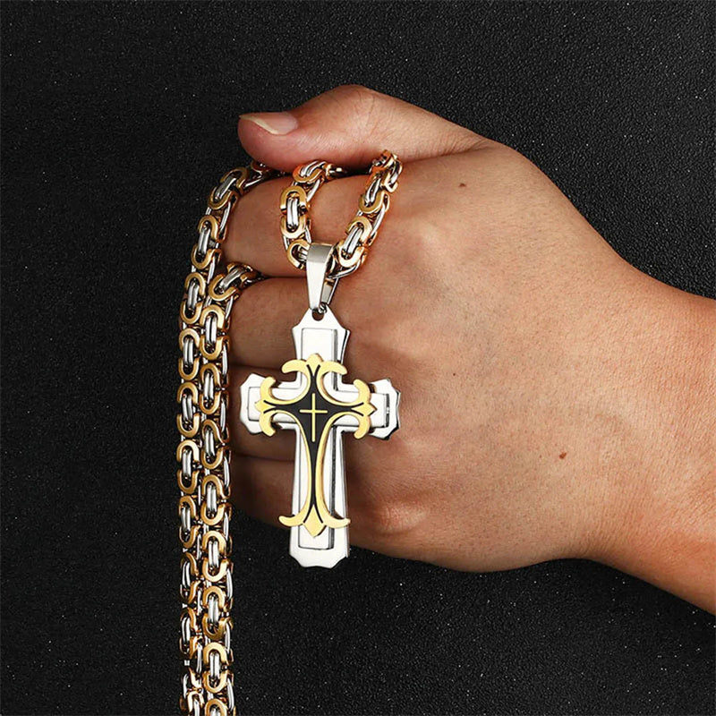 Hand holding a gold chain with a silver cross pendant against a black background